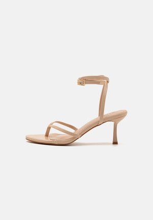Nude, strappy højhælede sandaler med en tynd ankelsnor og en afsmalnet hæl, der har en glat, blank finish og et minimalistisk design.