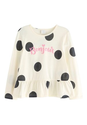 Chemise blanche à manches longues avec des pois noirs et un ourlet volanté. Elle présente le mot "Bonjour" en écriture cursive rose à l'avant.