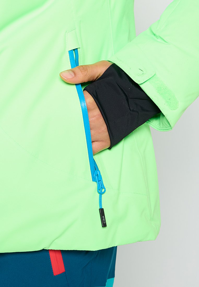 Helle grüne Jacke mit einer blauen Reißverschlusstasche und schwarzem Bund. Das Material scheint leicht zu sein; mit glatter Textur und sportlichem Design.
