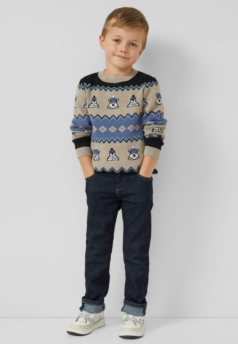 Sweter z dzianiny o jasnoszarej bazie, niebieskich akcentach i wzorach z niedźwiedziem polarnym. Połączony z ciemnymi dżinsami i białymi sportowymi butami. Prosty, casualowy design.