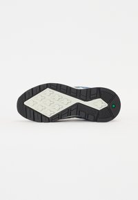 Sola do sapato atlético Timberland, apresentando um padrão de borracha preta, entressola branca e padrões de tração geométricos. Acentuada com detalhes em verde.