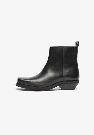 Glad zwarte leren enkellaars met lage, schuine hak en trekflap aan de achterkant, zijaanzicht op een witte achtergrond.