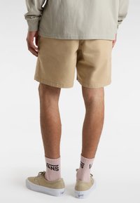 Khaki shorts i et letvægtsstof med en afslappet pasform, parret med beige sneakers og pink ribbede sokker med sort branding.