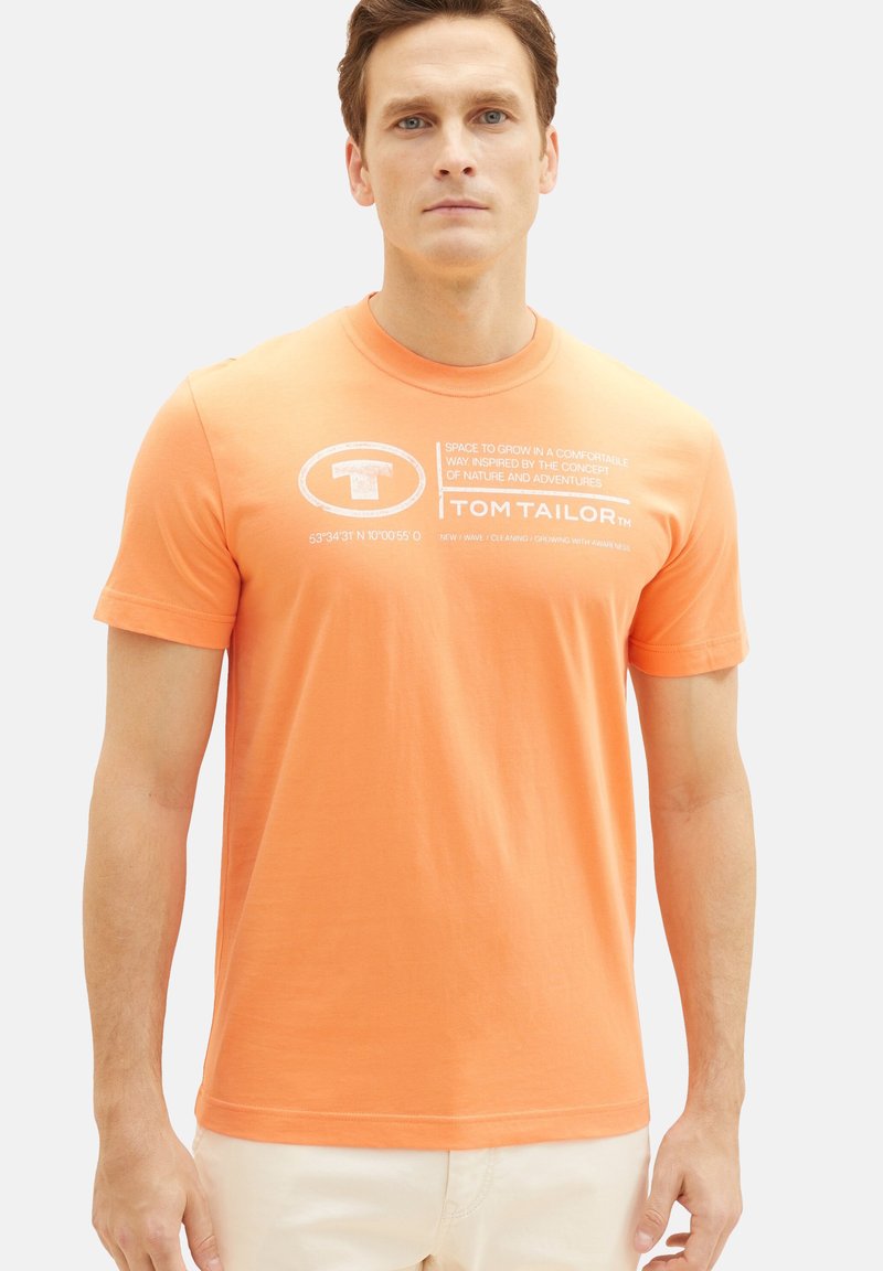 Oranje katoenen t-shirt met ronde hals, korte mouwen en witte bedrukte tekst met de merknaam "TOM TAILOR" en coördinaten.