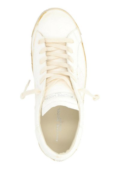 Sneaker bianco con tomaia in pelle testurizzata, punta rotonda e lacci piatti. Evidenti segni di usura sul bordo, logo stampato sulla soletta.