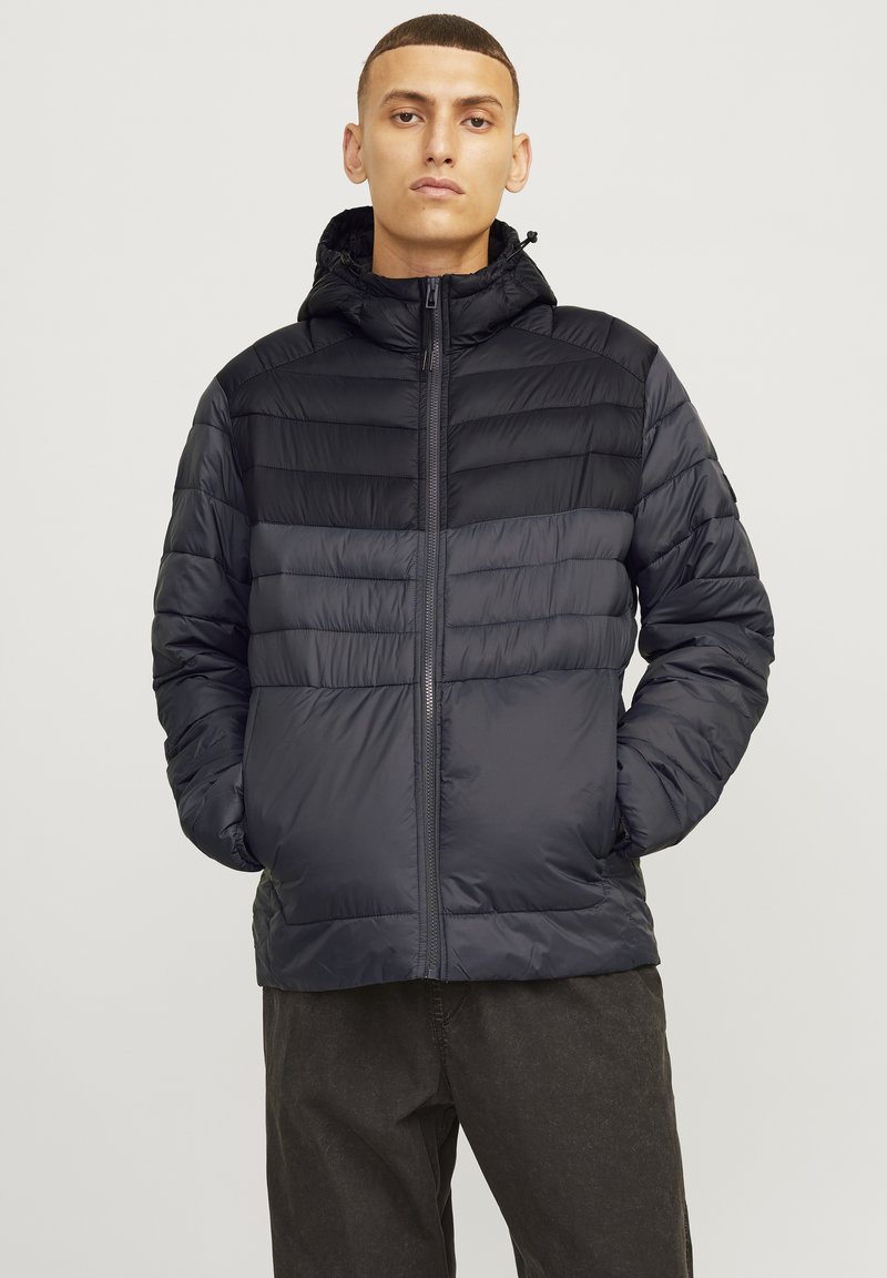 Black puffer jacket with a zip front, hood, and chevron quilted design. Made from lightweight, shiny material; features elastic cuffs.