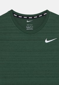 Grønn Dri-FIT t-skjorte med teksturert utseende, rund halslinning og en hvit Nike-logo på venstre bryst. Svart merkeetikett på kragen.