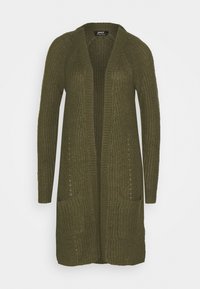 Oliivinvihreä neulottu neuletakki, jossa on pitkä etuosa, auki olevat mallit, ribbitekstuuri ja kaksi etutaskua, mikä korostaa rentoa, yliriittoista istuvuutta.