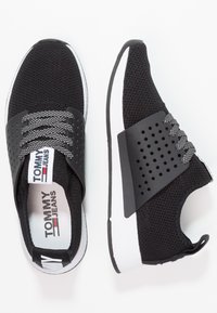 Czarno-białe trampki Tommy Jeans z siateczkowej tkaniny, perforowanym paskiem, wzorzystymi sznurówkami oraz logo na wkładce i języku.