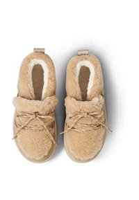 Beige sko i imiteret pels med en blød krave og plyssede tekstur, med rund form, gyldne detaljer og flade snørebånd.