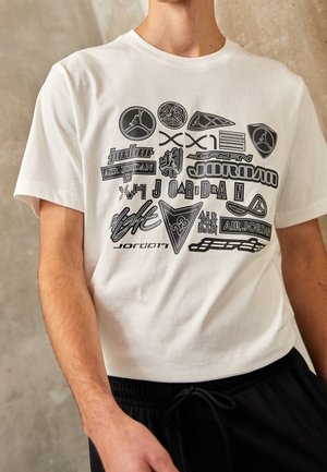 White cotton t-shirt featuring multiple black graphics and logos related to Air Jordan in various designs and shapes. Short sleeves, standard fit.