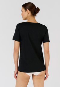 Camiseta negra de manga corta con cuello redondo, hecha de material suave. Corte recto, sin estampados ni acentos, mostrando un diseño minimalista.