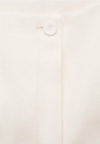 Bíla strukturovaná tkanina s jediným knoflíkovým zapínáním nahoře. Má čistý, rovný šev uprostřed.