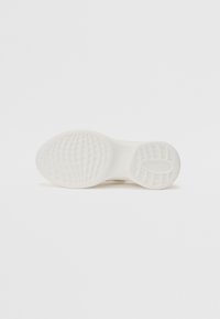Semelle de tennis blanche avec une surface en caoutchouc texturée, un motif antidérapant et des bords arrondis, conçue pour l'adhérence et la durabilité.