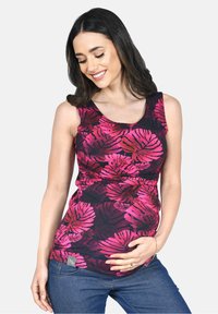 Top maternità nero con grande motivo a foglia rosa, scollatura a barca e dettaglio arricciato in vita. Abbinato a jeans blu.