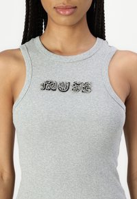 Siv estoque s tank top s črtami in besedo "MUSE" okrašeno s kristali. Izrez je krožen, material pa se zdi mehak in raztegljiv.