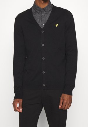 Zwarte cardigan met een v-hals, lange mouwen en knopen aan de voorkant. Heeft een klein geel logo op de linkerborst. Zachte textuur.