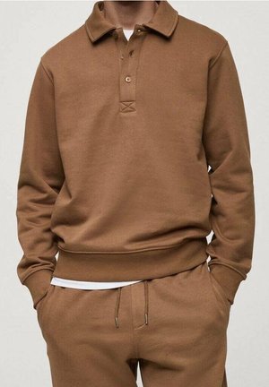 Jersey marrón de manga larga con cuello y botones, combinado con pantalones marrones con cordón a juego y una camisa blanca que asoma por debajo.