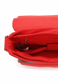 Czerwona torba na ramię z klapką, wyposażona w wewnętrzną kieszeń na suwak i wiele przegródek. Gładka struktura i złote elementy ozdobne.