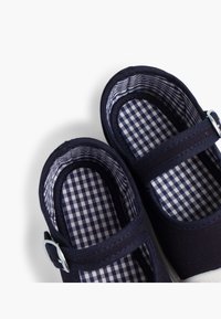Scarpe in canvas blu navy con fodera a quadri, forma arrotondata e cinturino regolabile con hardware argentato.