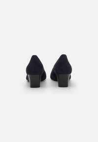 Scarpe con tacco alto in suede blu navy, con punta affusolata e tacco spesso nero, caratterizzate da una texture liscia e un design classico.