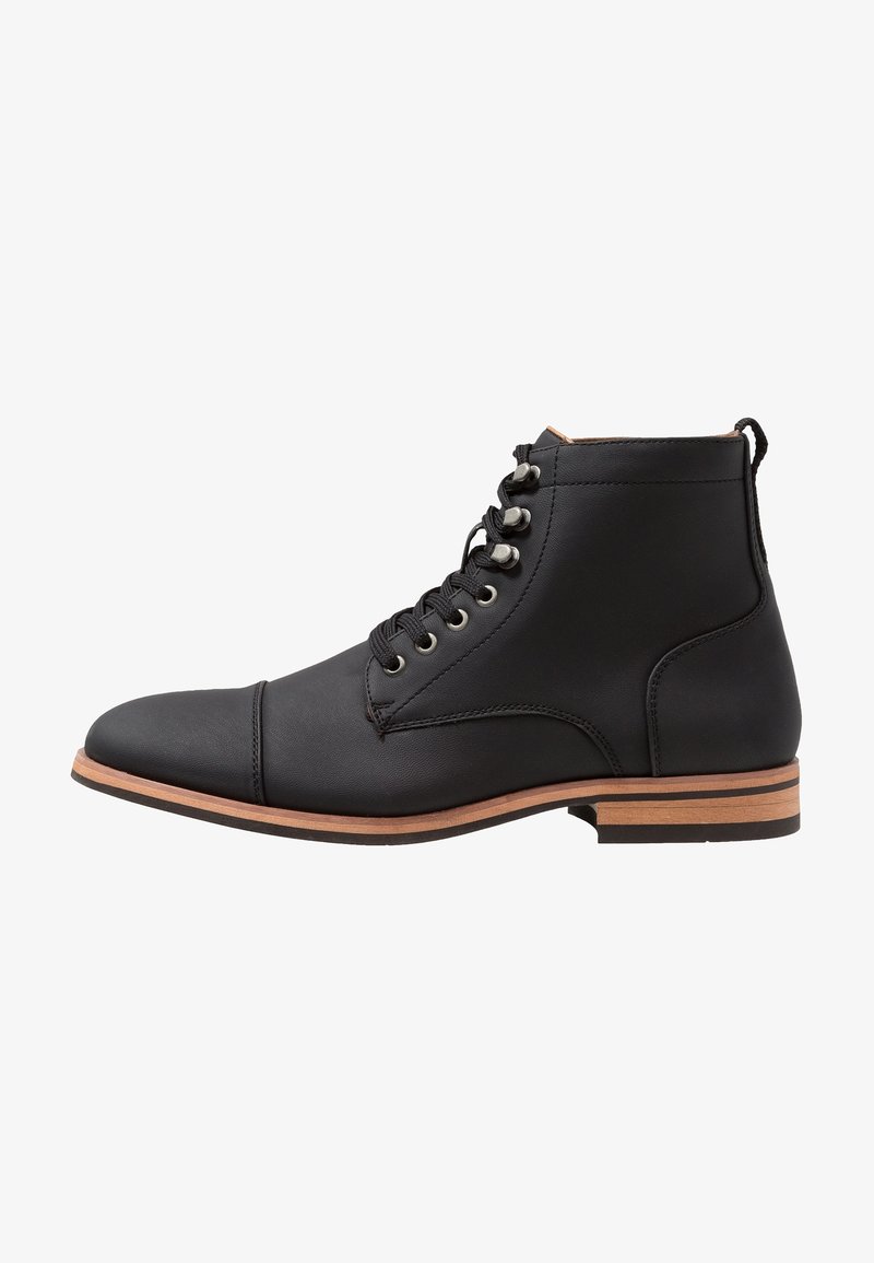 Bottine en cuir noir avec lacets sur le devant, œillets métalliques et talon empilé marron, vue de côté extérieur sur fond blanc.