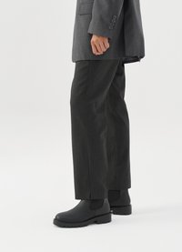 Pelēks, pielāgots bleizeris apvienots ar tumši pelēkiem, brīvi pieguļošiem biksēm un melniem čēlijas zābakiem ar biezu zoli. Gluda auduma ar smalkām striķēm.