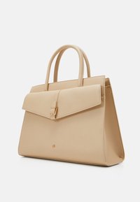 Beżowa, strukturalna torebka wykonana z gładkiej skóry, z klapkowym zamknięciem na złotą klamrę i dwoma górnymi uchwytami.
