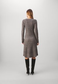 Robe tricotée côtelée dans des tons de gris, avec des manches longues et un ourlet évasé. Associée à des bottes noires jusqu'aux genoux. Texture lisse, silhouette ajustée.