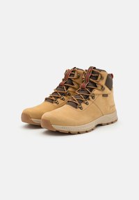 Tan hiking boots with brown accents, featuring a high shaft, lace-up design, and a textured rubber sole for traction.