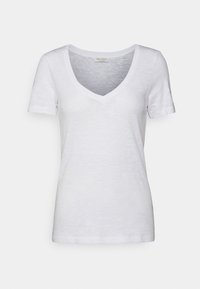 Camiseta blanca de manga corta y escote en V, confeccionada en una tela ligera con una textura sutil. Presenta una etiqueta cosida en el escote.