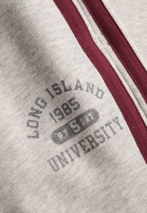 Jasnoszara tkanina z bordowym obszyciem zamka i nadrukowanym napisem "LONG ISLAND 1985 WEST UNIVERSITY."