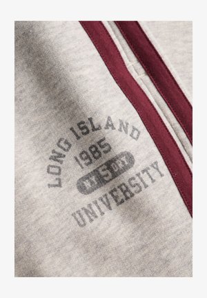 Jasnoszara tkanina z bordowym obszyciem zamka i nadrukowanym napisem "LONG ISLAND 1985 WEST UNIVERSITY."