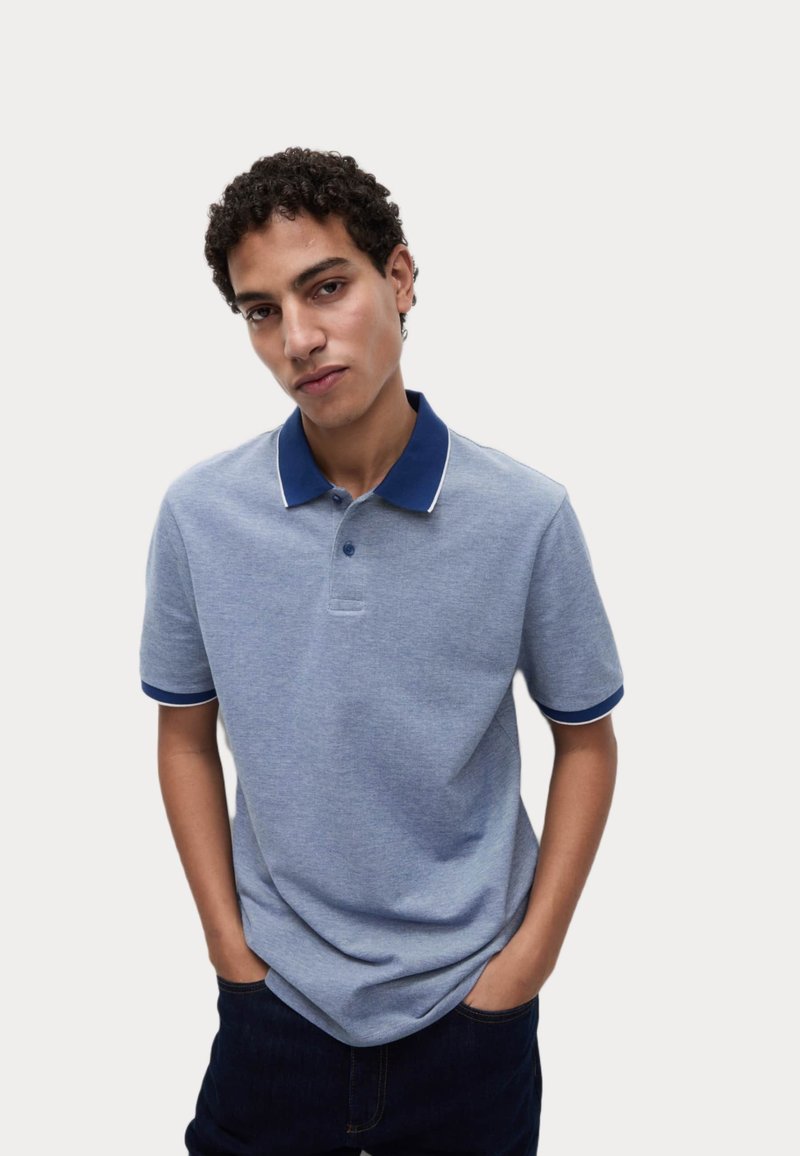 Polo bleu clair avec un col et des poignets de manches dans un bleu foncé contrastant, doté de trois boutons et d'un tissu doux et texturé.