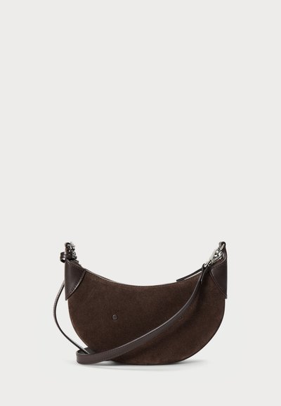 Brūnas zamšādas crossbody soma ar izliekta formu. Tumšas ādas akcenti un noņemama siksna. Sudraba aksesuāri tuvumā pie rāvējslēdzēja.
