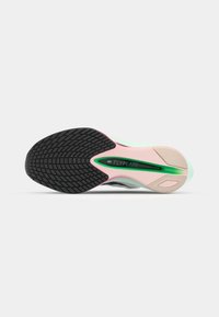 Nike Flyplate sneaker outsole featuring a textured black rubber surface, pink and green accents, and a smooth mint green midsole.