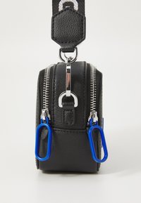 Black faux leather bag with silver zippers, blue accents, and metal hardware. Features a compact rectangular shape and a detachable strap.