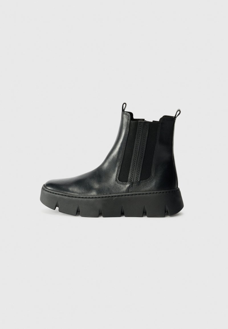 Bottines noires en cuir avec des panneaux élastiques sur les côtés, bout arrondi, et semelle en caoutchouc épaisse avec un bord cranté. Deux languettes pour un enfilage facile.