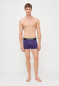 Fioletowe bokserki z fakturowanym wzorem, czarny elastyczny pas w talii z logo "DSQUARED2". Dopasowany krój na modelu bez koszuli.