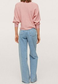 Vaaleanpunainen ribbineulottu neule, jossa väljä istuvuus ja laskosolkapäät, yhdistetty vaaleansinisistä leveälahkeisista farkuista, joissa on takataskut.