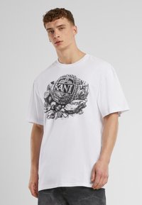 White cotton t-shirt featuring a black graphic design with the word "KANI" and various detailed elements, including cars and patterns.