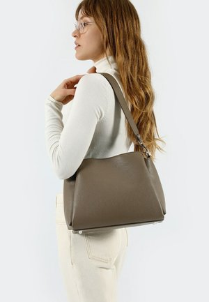 Sac à épaule en cuir marron avec une finition texturée, forme trapézoïdale et une bandoulière amovible, ornée de détails en métal argenté.
