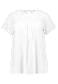 Biała krótka bluzka z krótkim rękawem, z ażurowym wzorem na rękawach i karczku. Miękka bawełniana tkanina, luźny krój, zapięcie na plecach z otworem.