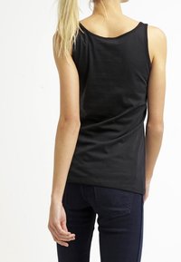 Svart ärmlös linne i slätt tyg med avslappnad passform. Har en rundad halsringning och en enkel, ren design.