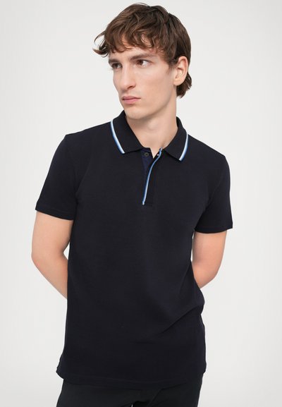Polo shirt azul escuro com colarinho abotoado, com detalhes em azul claro, mangas curtas e design ajustado. Tecido suave e texturizado com fendas laterais.