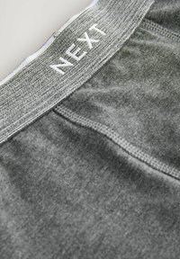 Grå herreboxershorts med et vævet elastisk bånd mærket "NEXT." Har flade sømme og en glat, blød tekstur.