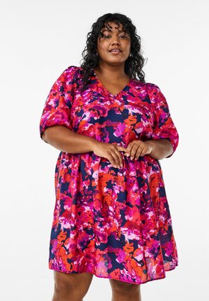 Korte mouwen, V-hals jurk met een uitlopende silhouet. Kenmerkt zich door een levendig bloemenpatroon in roze, rood en marineblauw. Lichtgewicht stof.