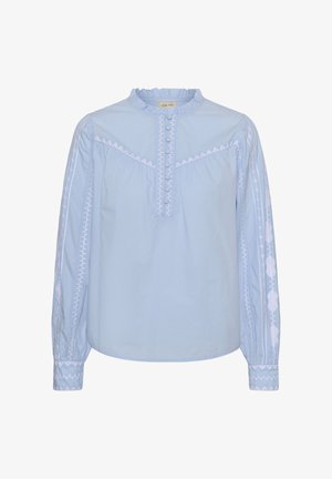 Blusa de algodón azul claro con mangas largas abullonadas, cuello con volantes, tapeta con botones y detalles bordados en blanco en las mangas.