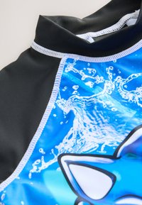 Kurzärmeliger Rashguard in Schwarz und Blau. Mit Wasser- und Tierdesign. Hergestellt aus dehnbarem, leichtem Material.
