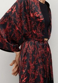 Kimono en satin noir avec motifs de feuilles rouges et d'oiseaux, doté de manches larges, d'une ceinture à nouer et d'une coupe décontractée. Le tissu texturé ajoute de la profondeur.